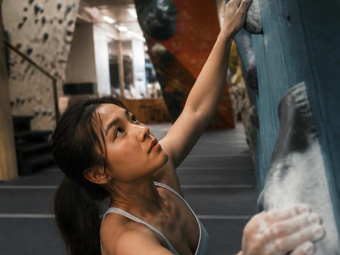 Maya Chen looking up at a climbing hold